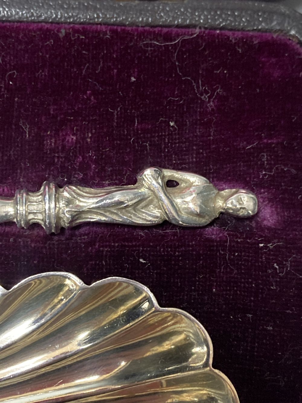 A cased pair of late Victorian silver serving spoons, with shell bowls and figural terminals,